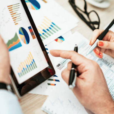 Two professionals in office, one young female and one male, in formal clothing, dealing with finance, financial issues, investments, and market analysis. Image taken from above - overhead image, representing teamwork and collaboration, brainstorming and progressive innovative work.